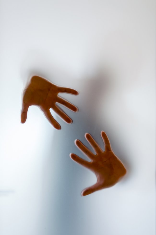 Shadowy human figure behind a frosted glass